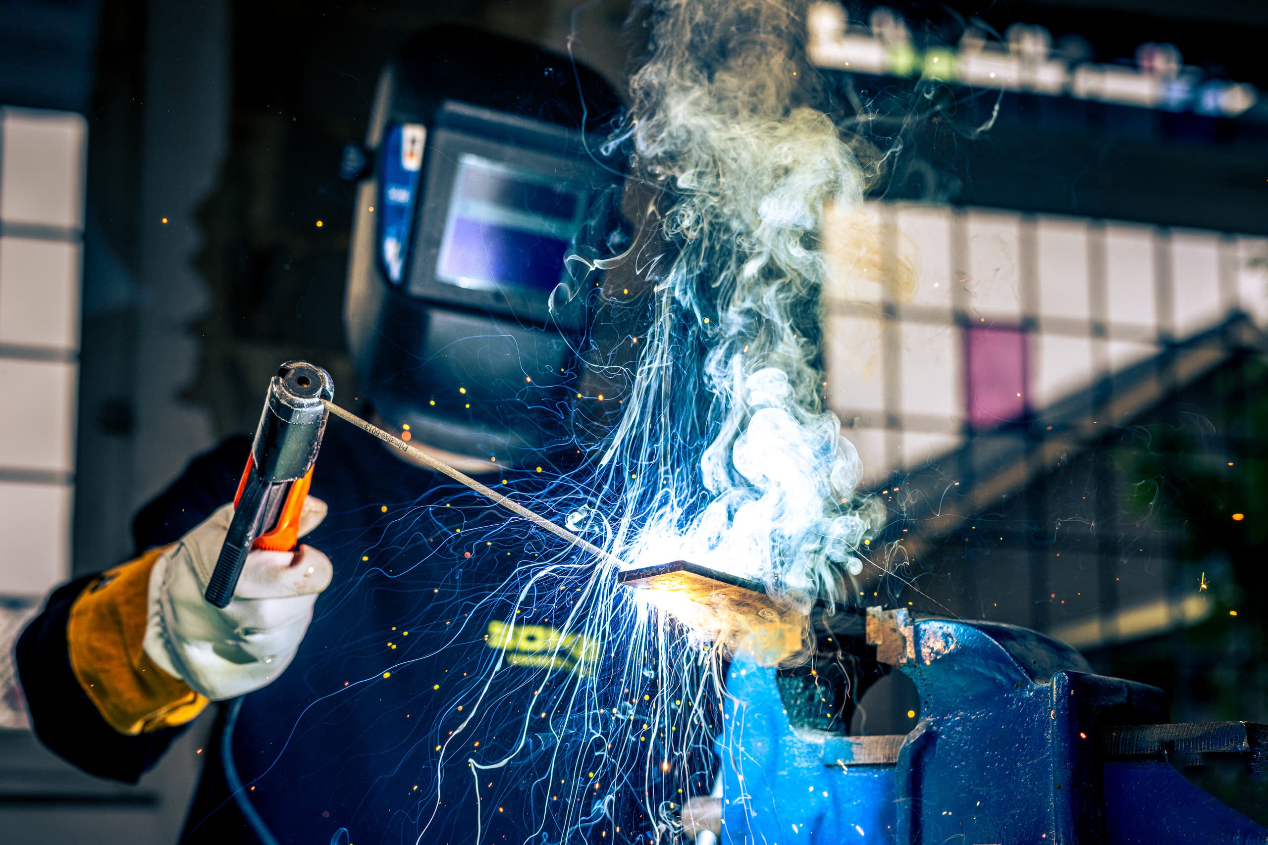 Lasser van SOMA Vakmeesters aan het werk in een werkplaats, de rook trekt omhoog langs het laswerk